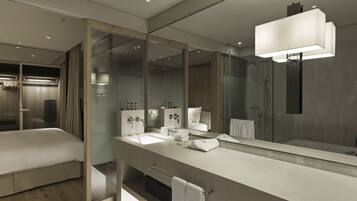 Une salle de bain moderne dotée d’un grand miroir, d’une baignoire, d’une douche et d’un meuble-lavabo avec un évier et un porte-serviettes.