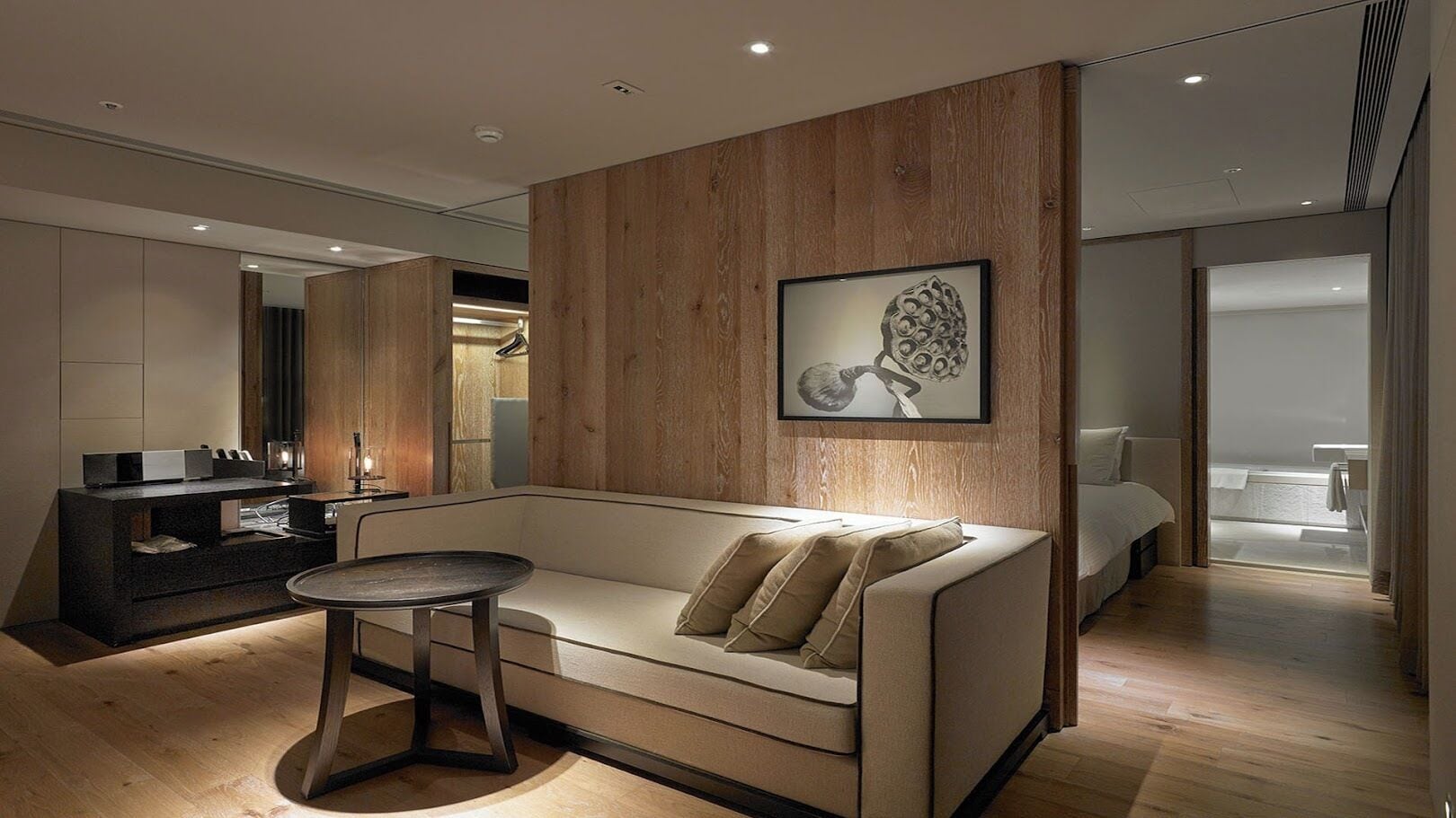 Une chambre d’hôtel moderne avec un canapé, une petite table ronde et un mur décoratif en bois.