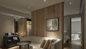 A modern living room with a wooden accent wall, a framed artwork, a sofa, and a small round table. - Gloria Residence (Taipei)