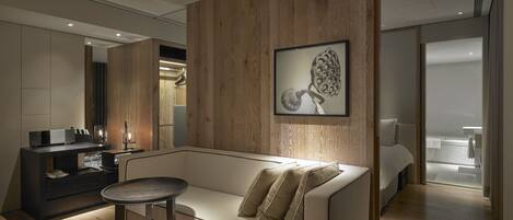 A modern living room with a wooden accent wall, a framed artwork, a sofa, and a small round table.