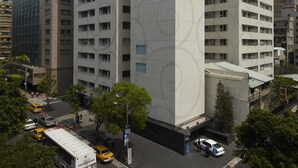 A modern high-rise building with a unique facade, surrounded by urban streets and vehicles. - Gloria Residence (Taipei)