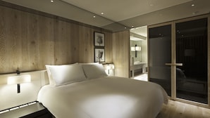 A modern bedroom with a large bed, wooden panel walls, and a sliding glass door leading to a bathroom. - Gloria Residence (Taipei)