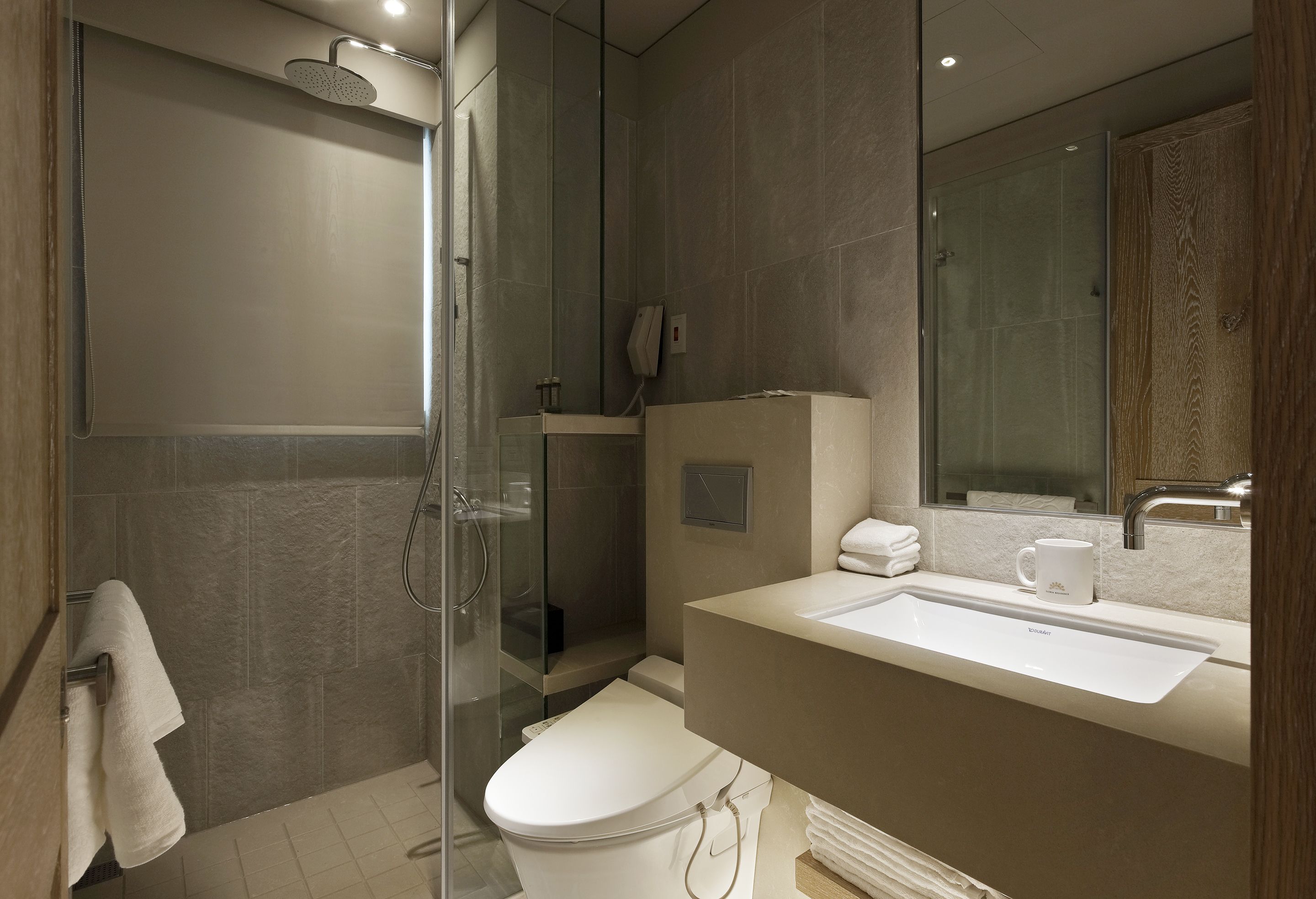 A modern bathroom with a glass-enclosed shower, a white sink, and a toilet.