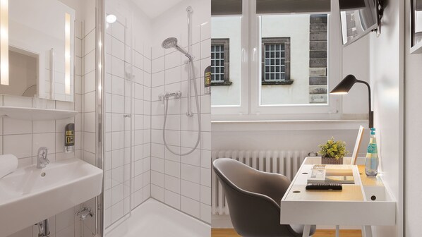 A modern bathroom with a shower, a sink, and a desk with a chair. - Beethoven Hotel Dreesen - furnished by BoConcept (Bonn)
