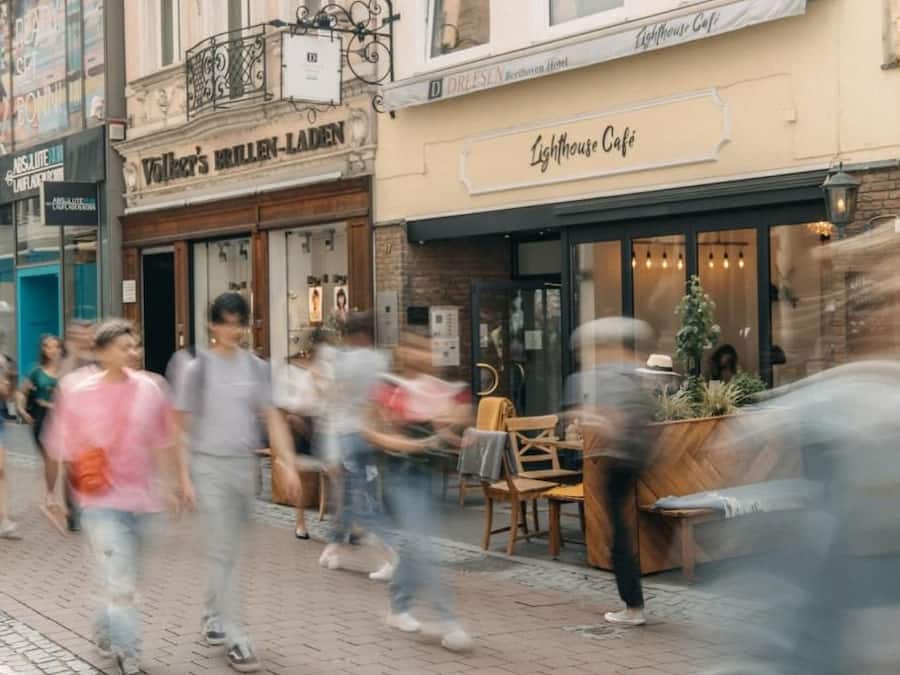 A street scene with a café named 'Lighthouse Café' and a shop called 'Volker's Brillenladen'.