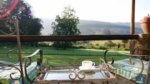Un balcon avec une table, une tasse et une vue sur un paysage verdoyant.