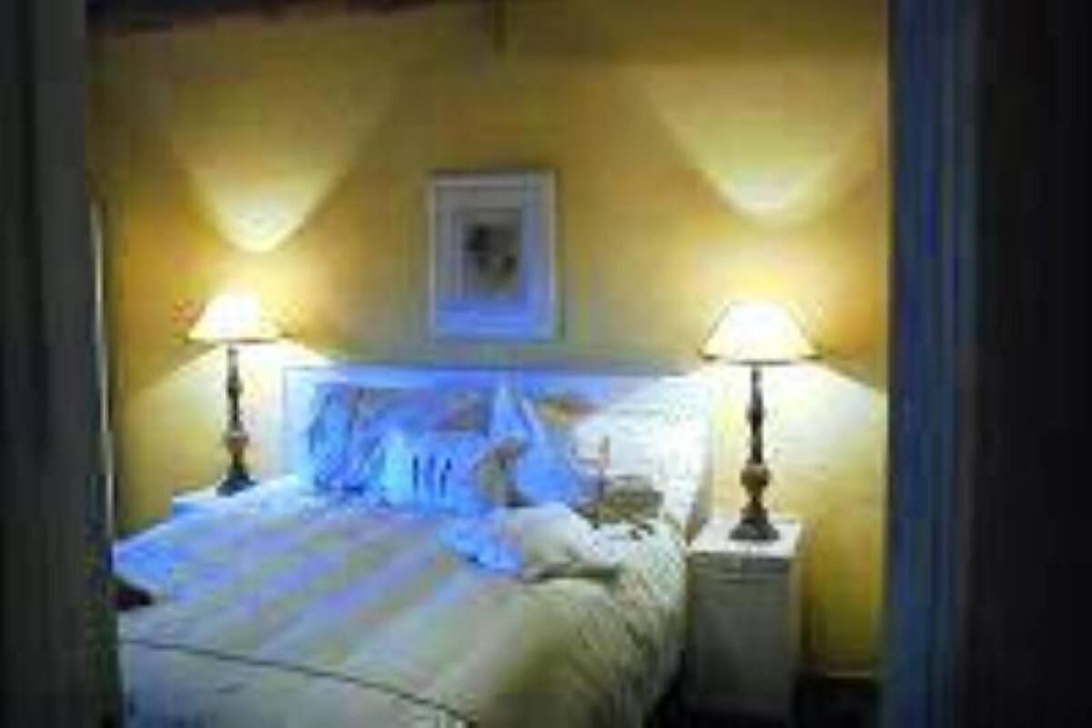 A bedroom with a bed, two bedside lamps, and a framed picture on the wall.