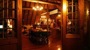 Une pièce mansardée chaleureuse, avec une table à manger en bois, des chaises et un lustre.