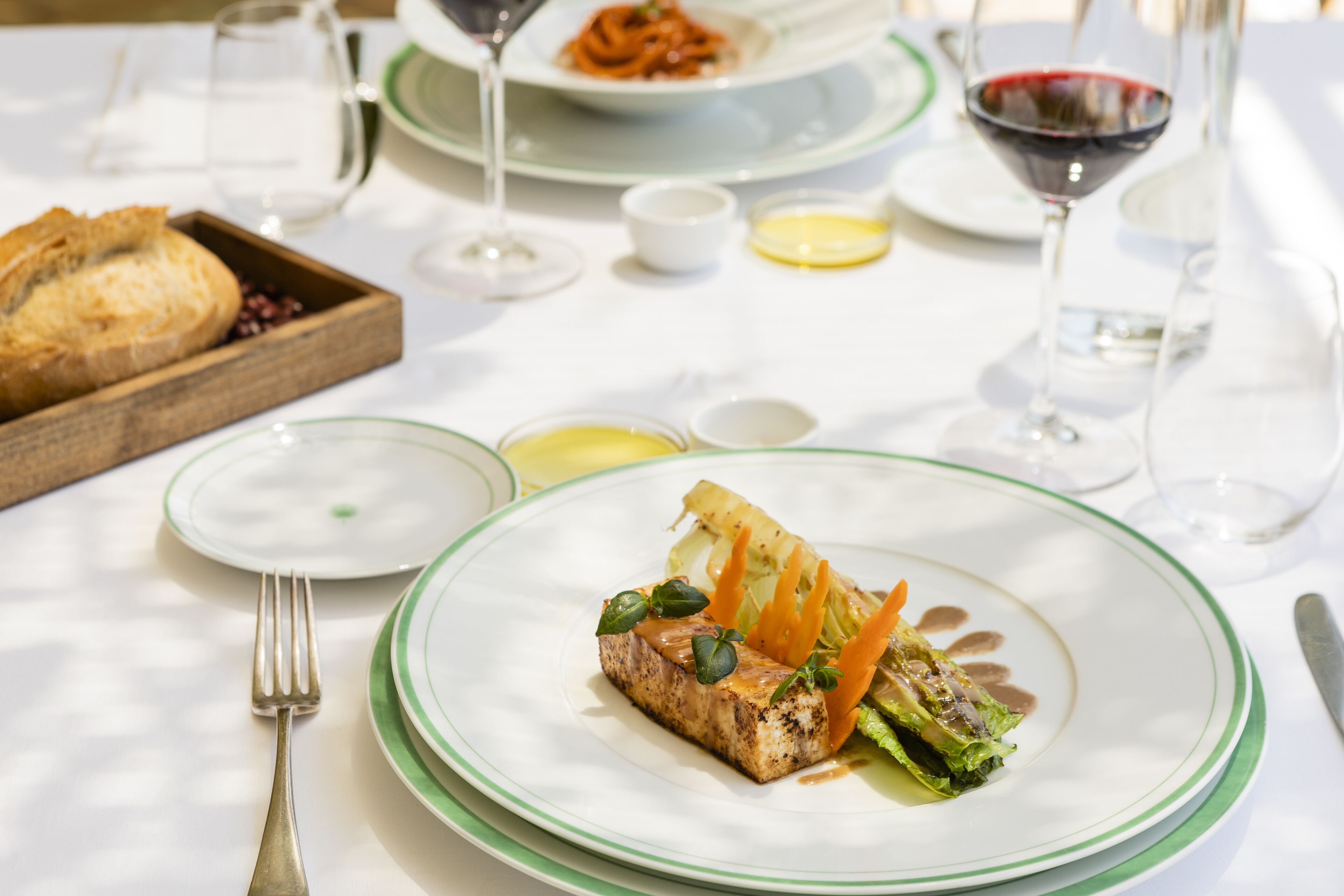 A dining table with a plate of food, a fork, and a wine glass.