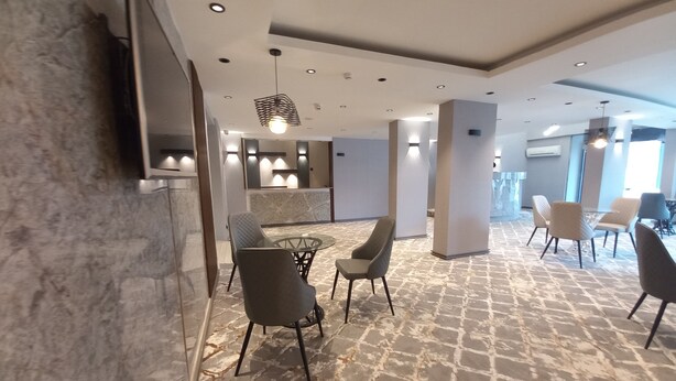 A modern hotel lobby with a marble floor, contemporary furniture, and recessed lighting.