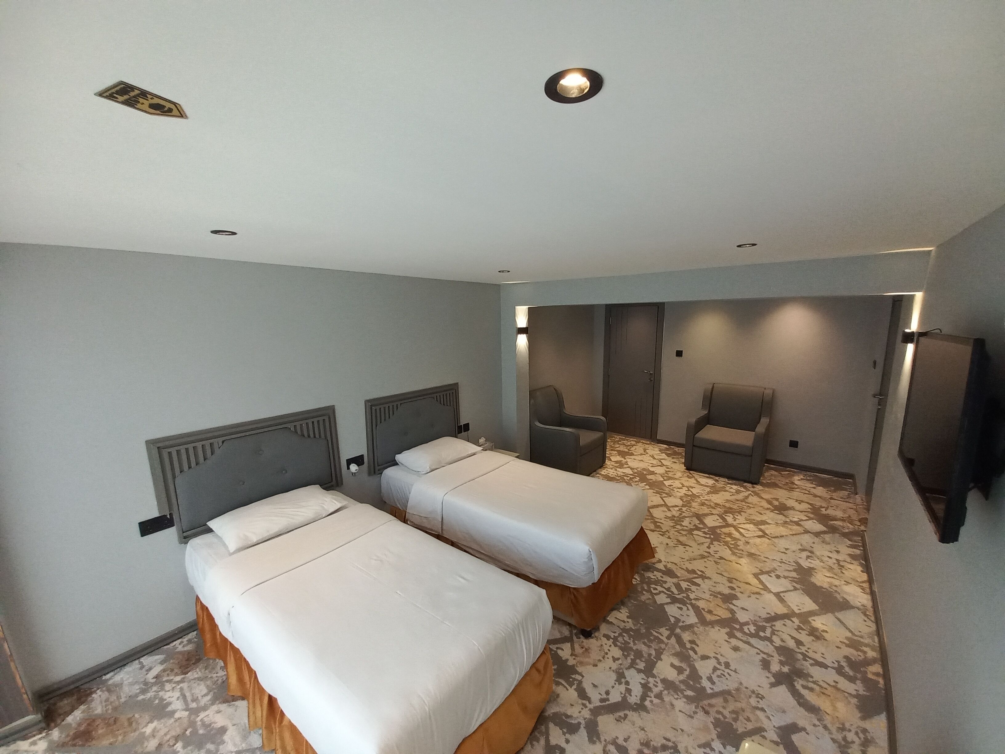 A hotel room with two beds, a seating area with chairs, and a television.