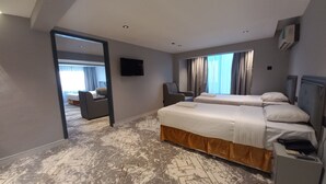 A hotel room with a large bed, a desk, a chair, a TV, and a window with curtains.