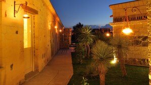 Un patio con un edificio de piedra, un camino y luces colgantes.