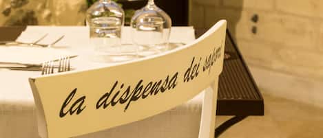 A table with a sign reading "la dispensa dei saponi" and a view of a stone wall and building in the background.