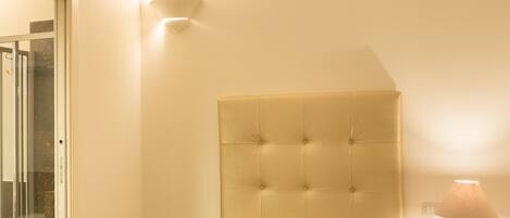 A hotel room with a bed, a nightstand, a lamp, and a door leading to a bathroom.