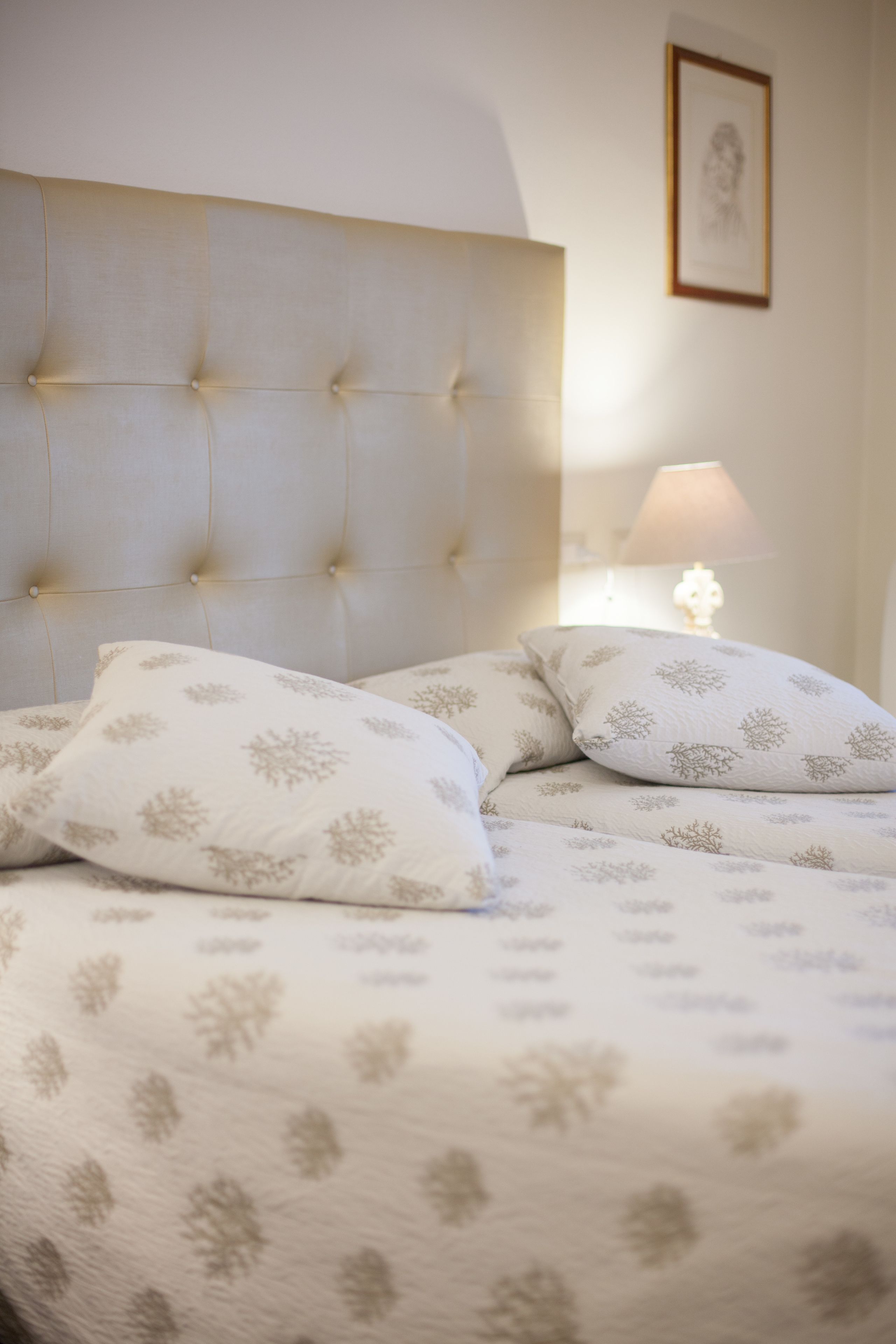 A neatly made bed with a tufted headboard and patterned bedding.