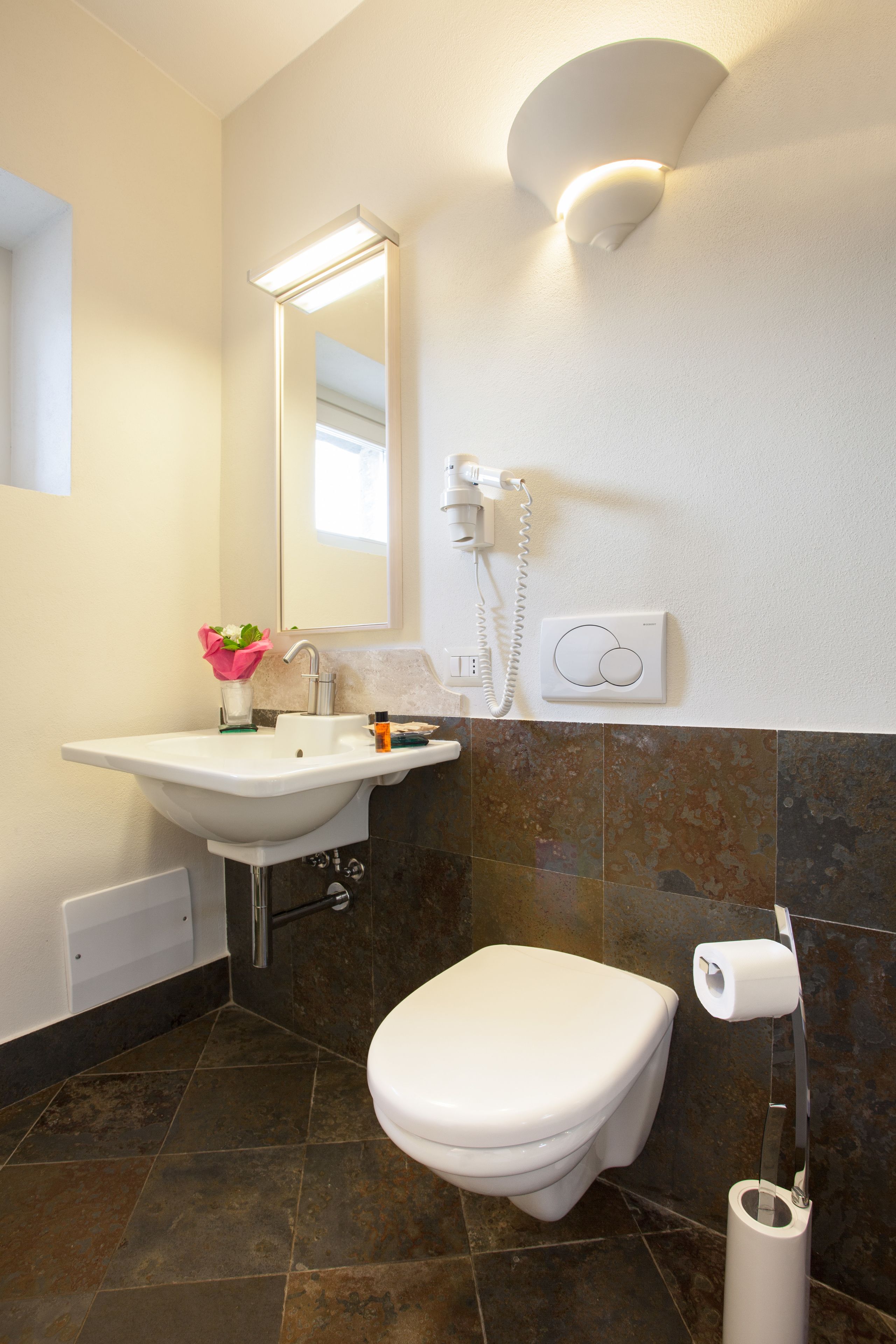 A bathroom with a white sink, a toilet, a mirror, and a towel rack.