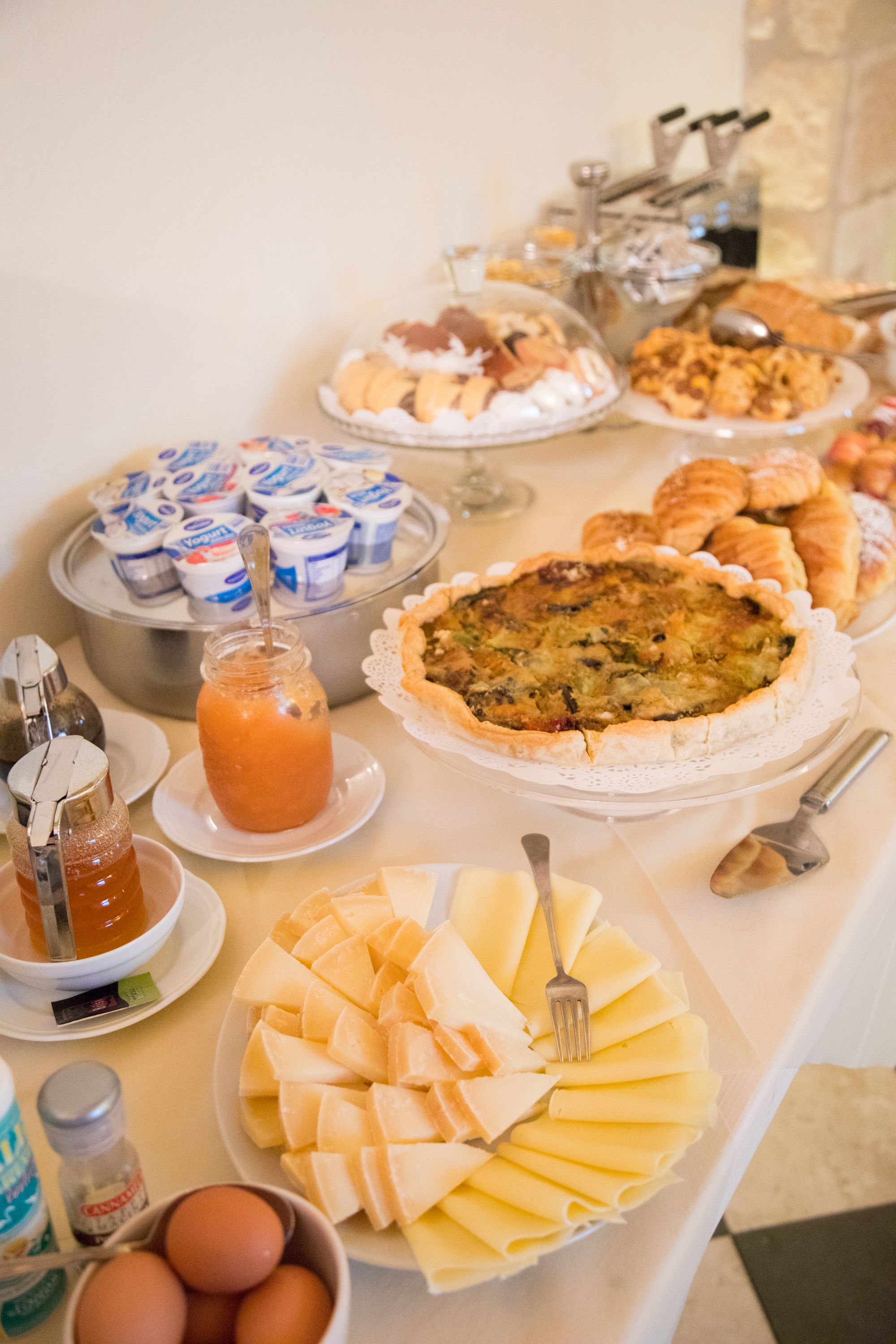 Ein reichhaltiges Buffet mit verschiedenen Speisen, darunter Quiche, Gebäck, Käse und Soßen.