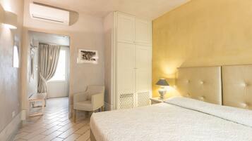 A hotel room with a bed, a chair, a wardrobe, and a window with curtains.