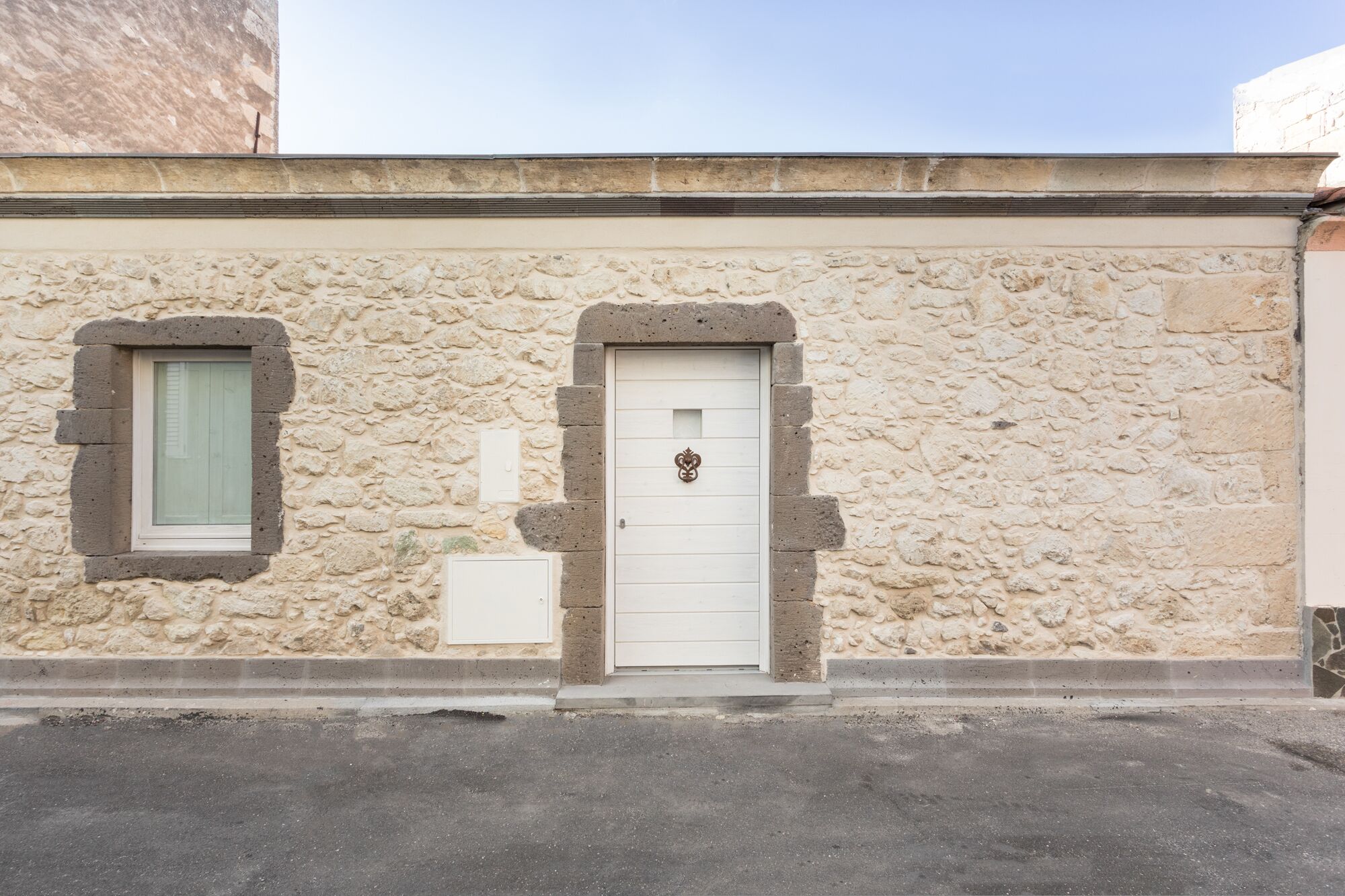 Un edificio de piedra con una puerta blanca y un pequeño ventanal.