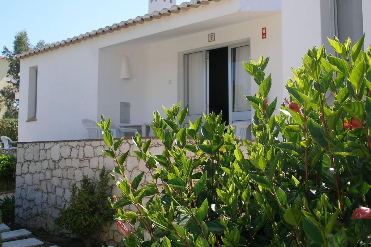 Un bâtiment blanc avec un mur en pierre, une porte et une fenêtre.