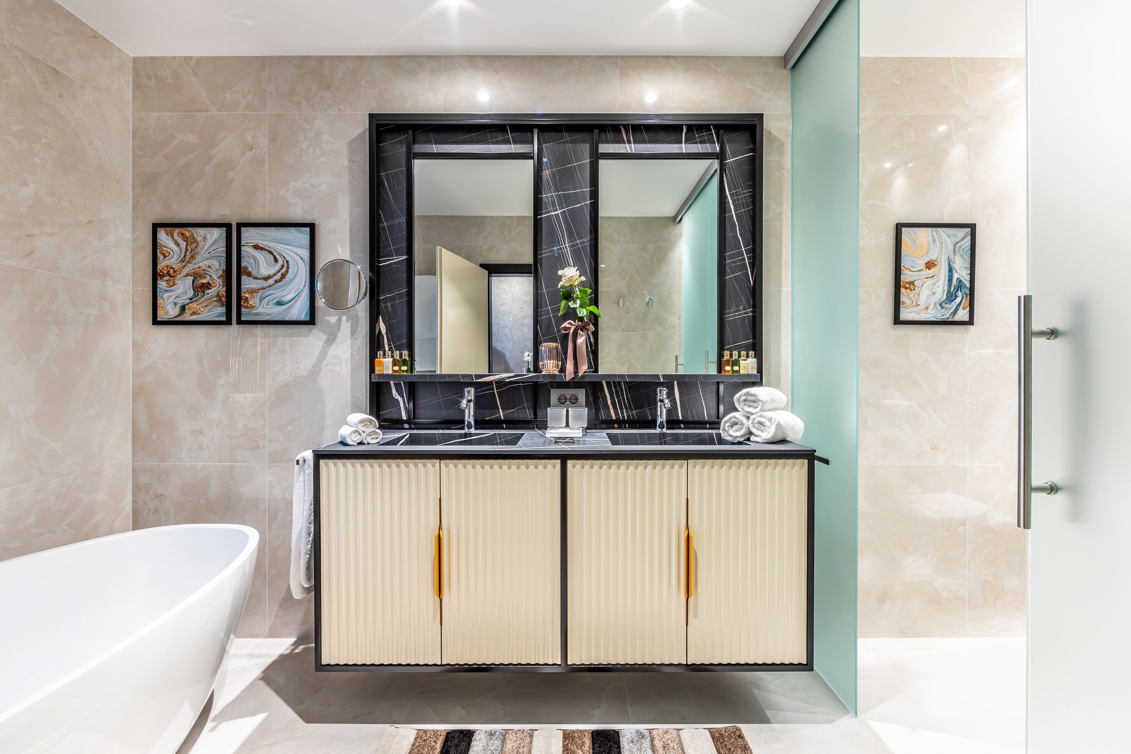 Un bagno moderno con una vasca da bagno indipendente, un doppio lavabo con un ampio specchio e piastrelle in marmo.