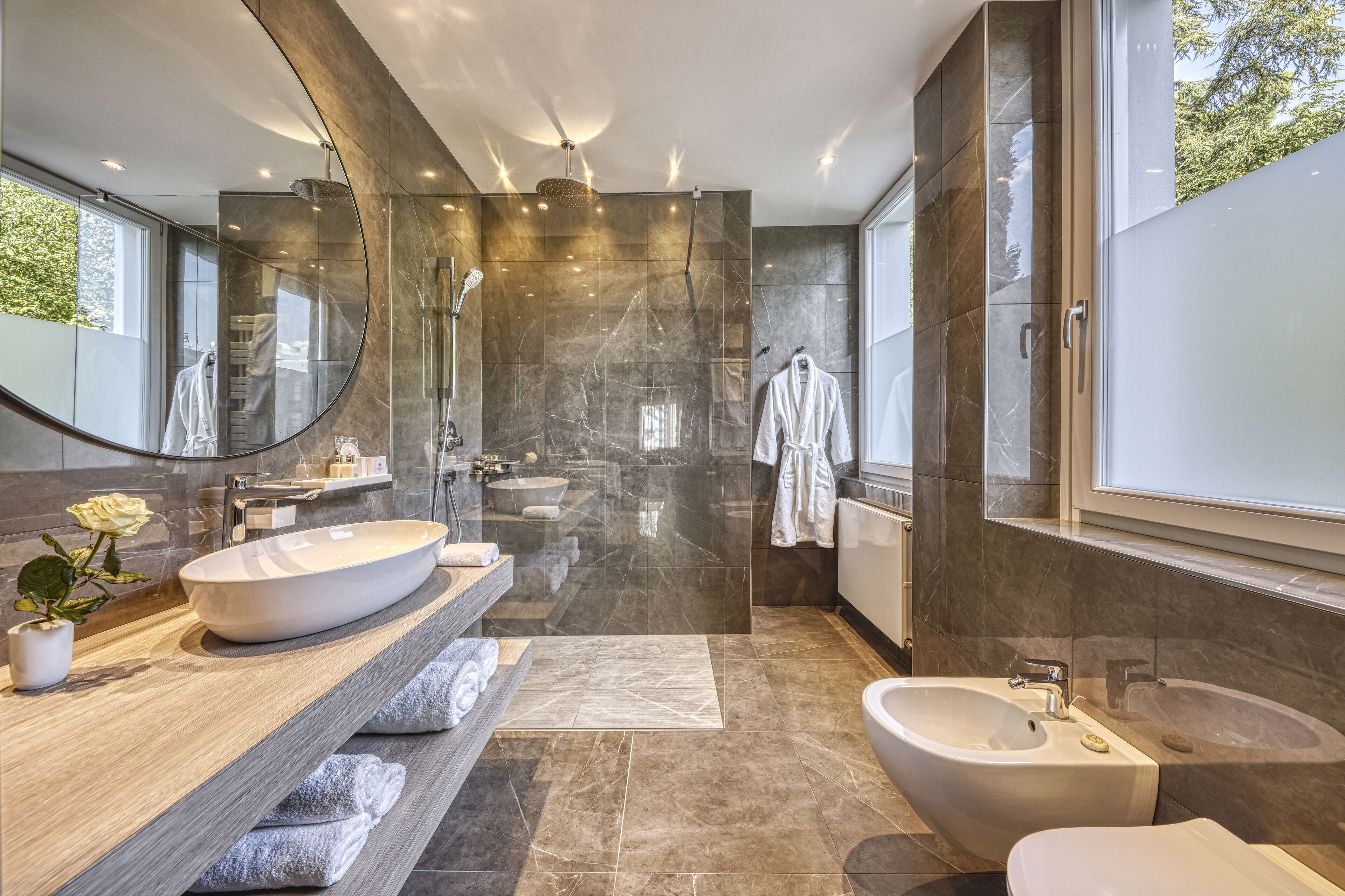 A modern bathroom with a large mirror, a freestanding bathtub, a vanity with a large sink, and a shower area.