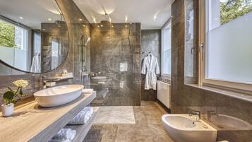 A modern bathroom with a large mirror, a freestanding bathtub, a vanity with a large sink, and a shower area.