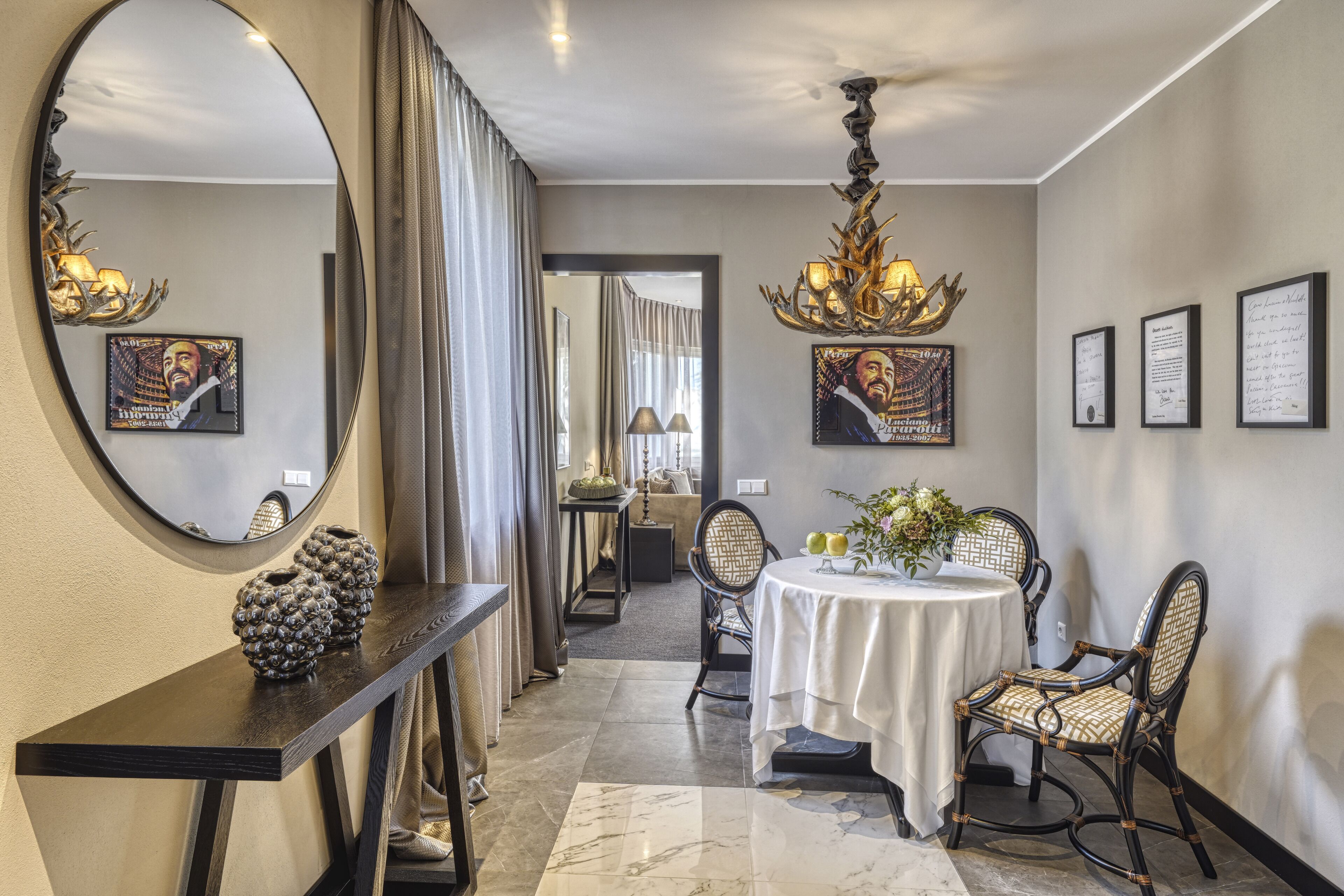 A dining area with a round table, two chairs, a mirror, and framed artwork on the walls.