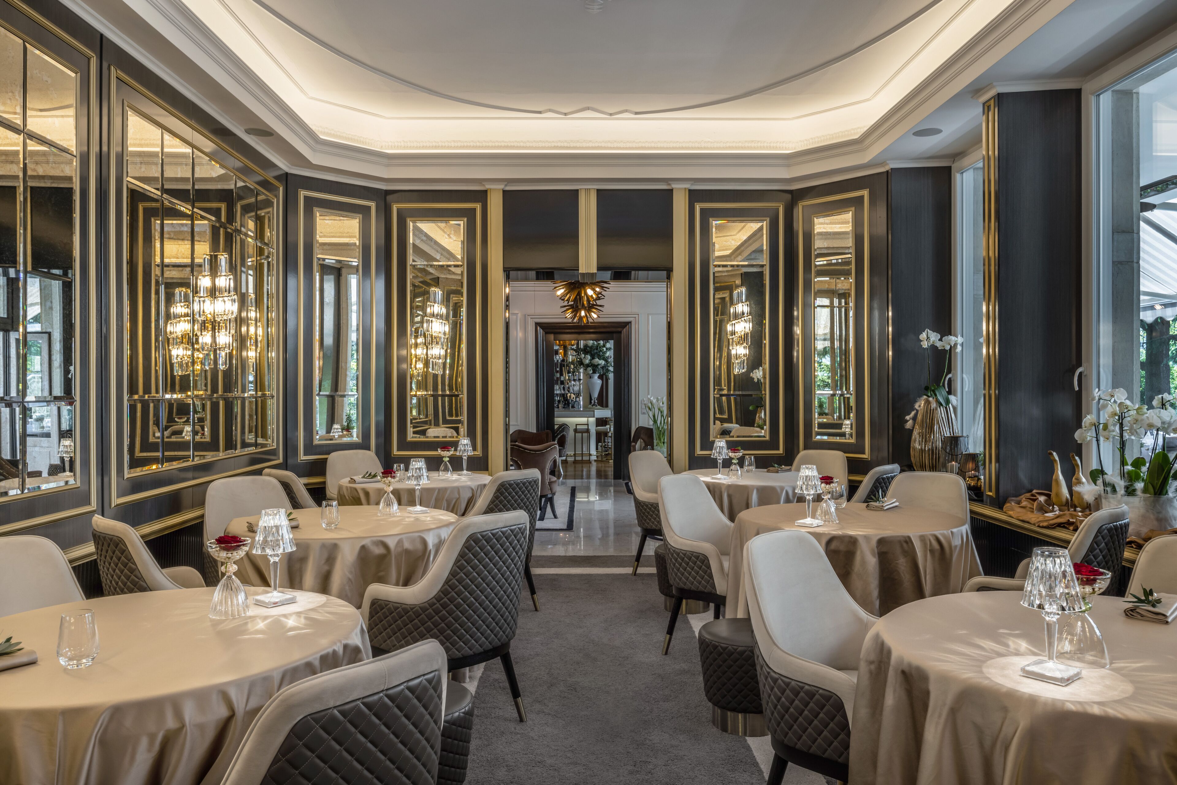 A luxurious dining area with round tables, elegant chairs, and chandeliers.