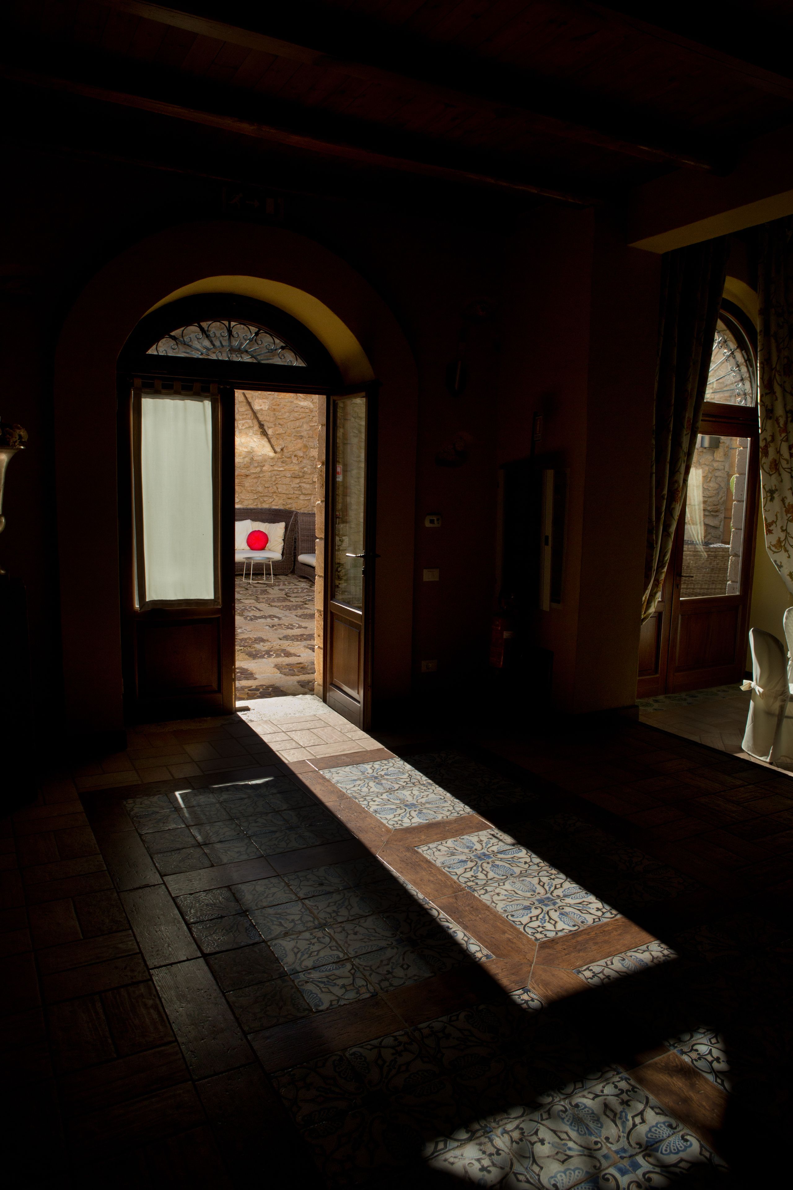 An arched doorway leading to an outdoor area with a patterned rug on the floor.