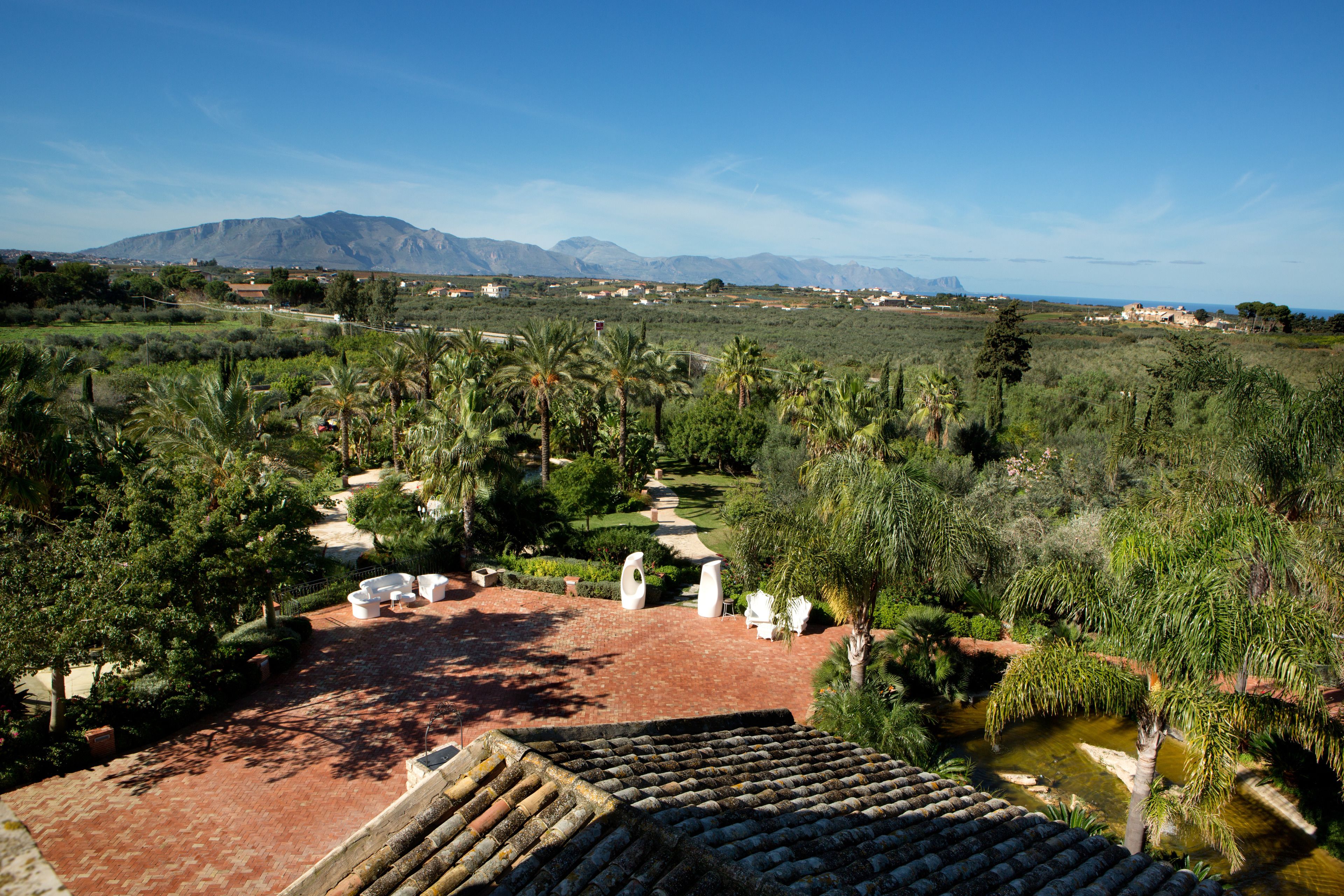 A terraced garden with palm trees, a brick pathway, and a view of distant mountains.