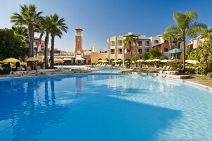 Una piscina techada, una piscina al aire libre, sombrillas