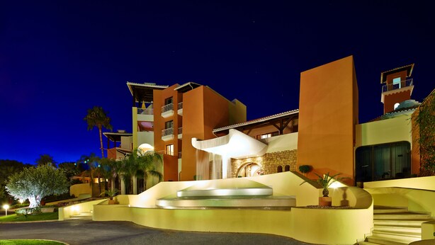 A modern hotel with a curved entrance, a central water feature, and multiple balconies. - Four Seasons Vilamoura (Loulé)