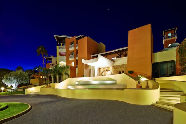A modern hotel with a curved entrance, a central water feature, and multiple balconies. - Four Seasons Vilamoura (Loulé)