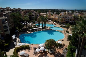Una piscina techada, una piscina al aire libre, sombrillas