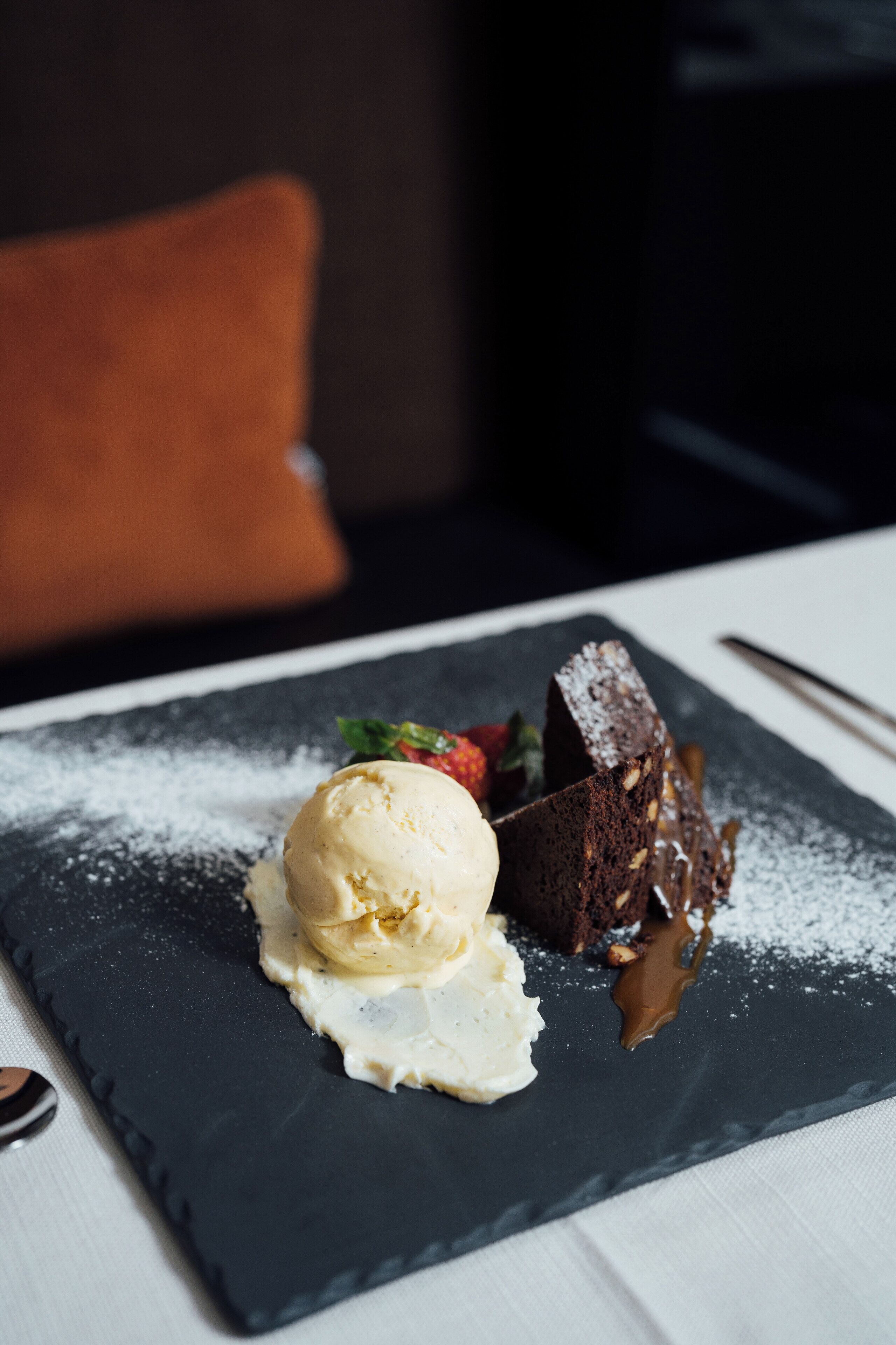 Un plato de postre con helado y pastel de chocolate, espolvoreado con azúcar glas.