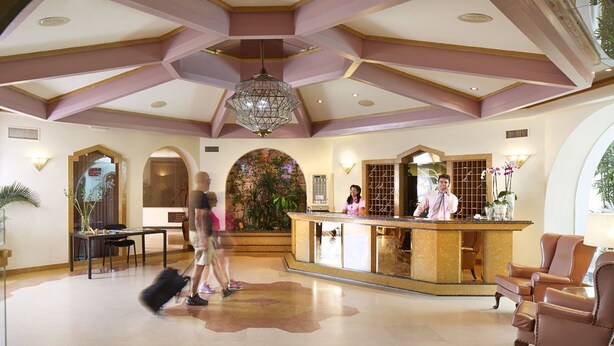 A hotel lobby with a reception desk, seating area, and a large decorative arch. - Four Seasons Vilamoura (Loulé)