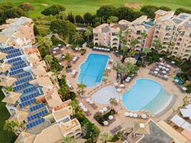 Un resort con varias piscinas, tumbonas y un campo de golf.