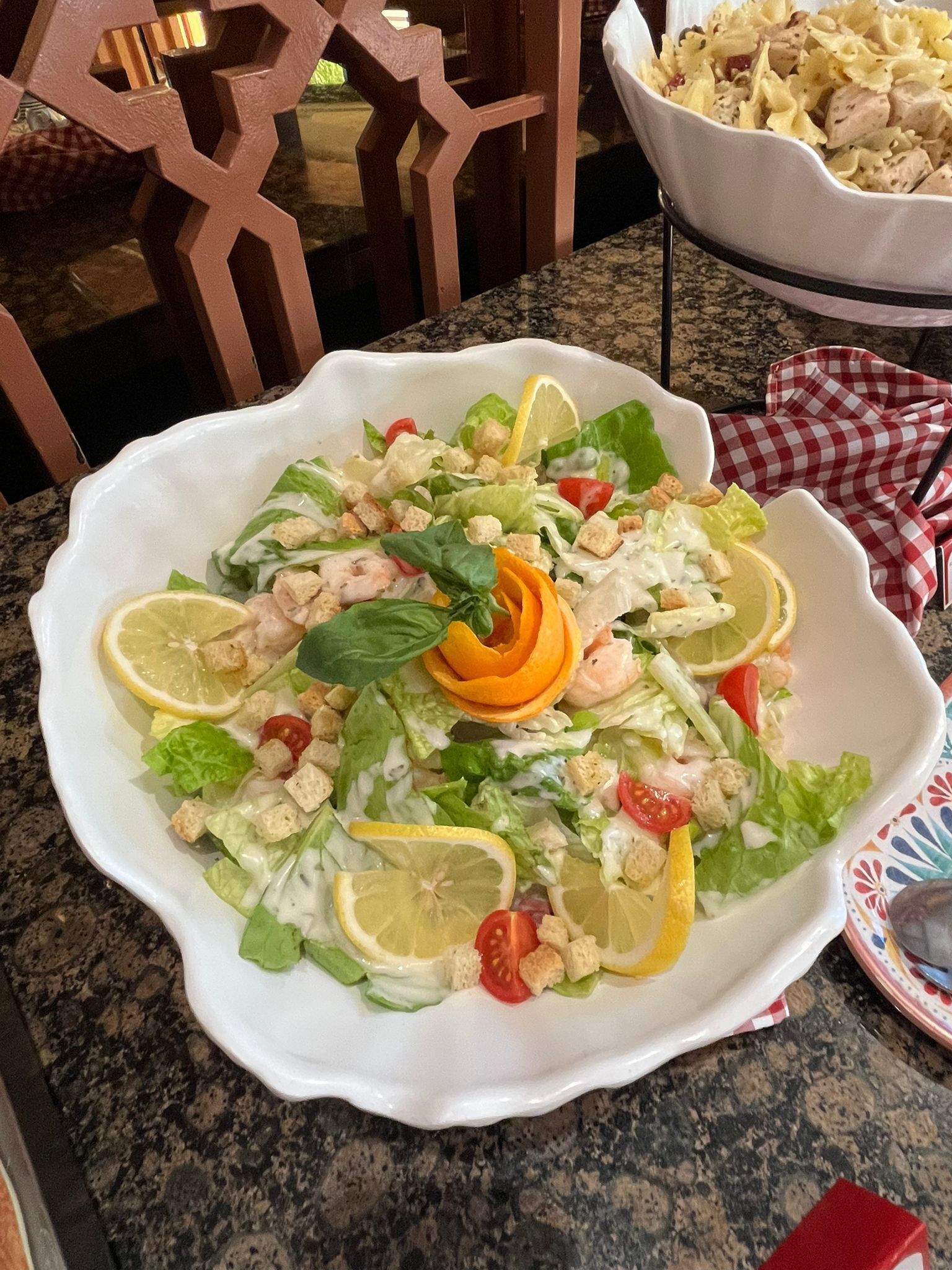 A white plate with a salad on a granite countertop.