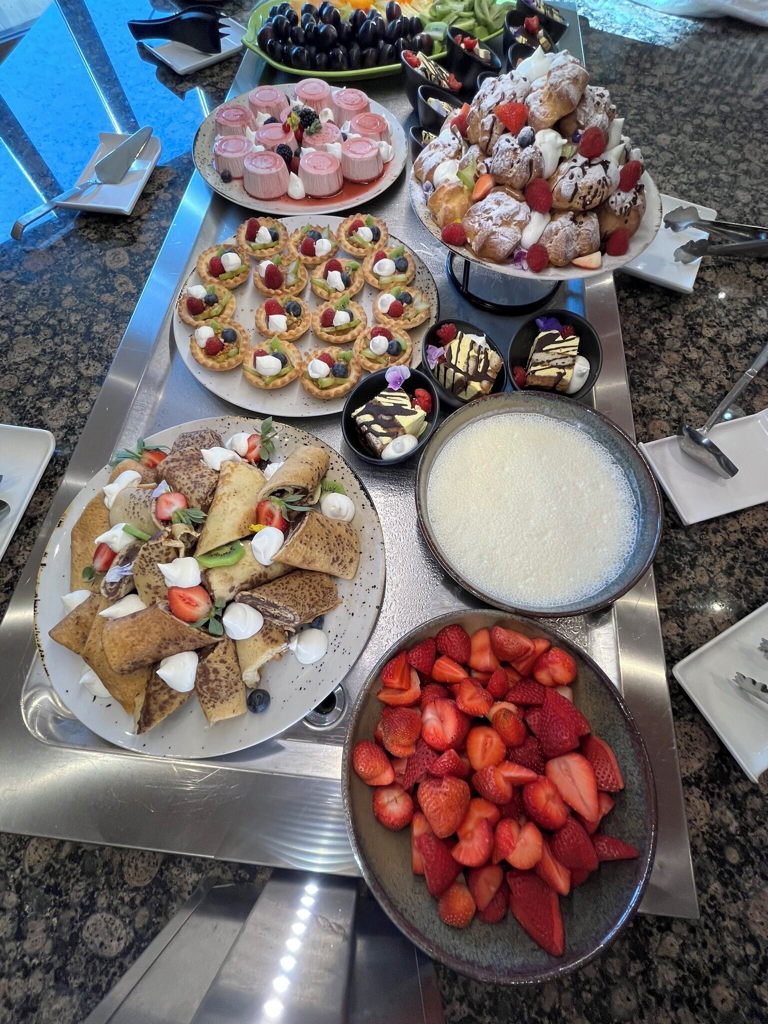 En buffet med et udvalg af mad, blandt andet kager, frugt og desserter.