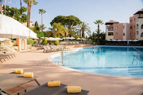 A pool area with lounge chairs, umbrellas, and a clear blue pool. - Four Seasons Vilamoura (Loulé)