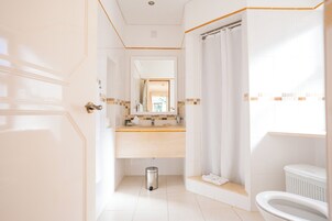Moderni kylpyhuone, jossa on valkoinen pesuallas, peili ja wc-istuin.
