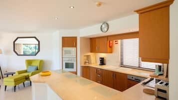 Una cocina moderna con armarios de madera, horno empotrado, microondas, cafetera y tostadora.