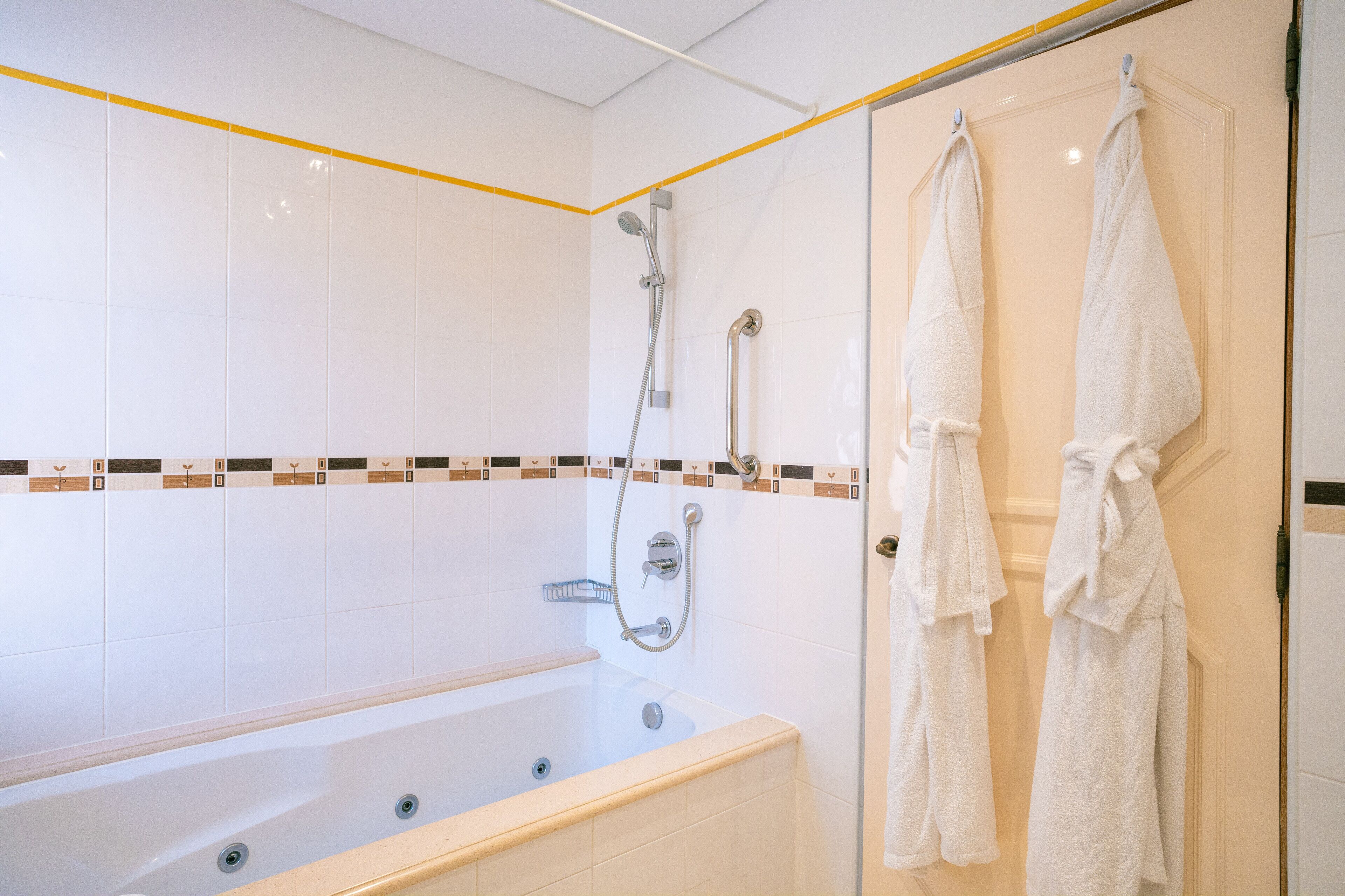 Une salle de bain avec une baignoire, une douche et deux serviettes suspendues à un porte-serviettes.