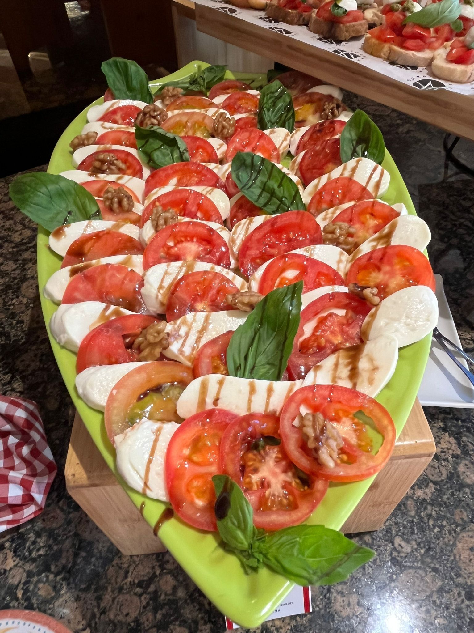 Una bandeja con ensalada caprese de tomates, mozzarella, albahaca y nueces.