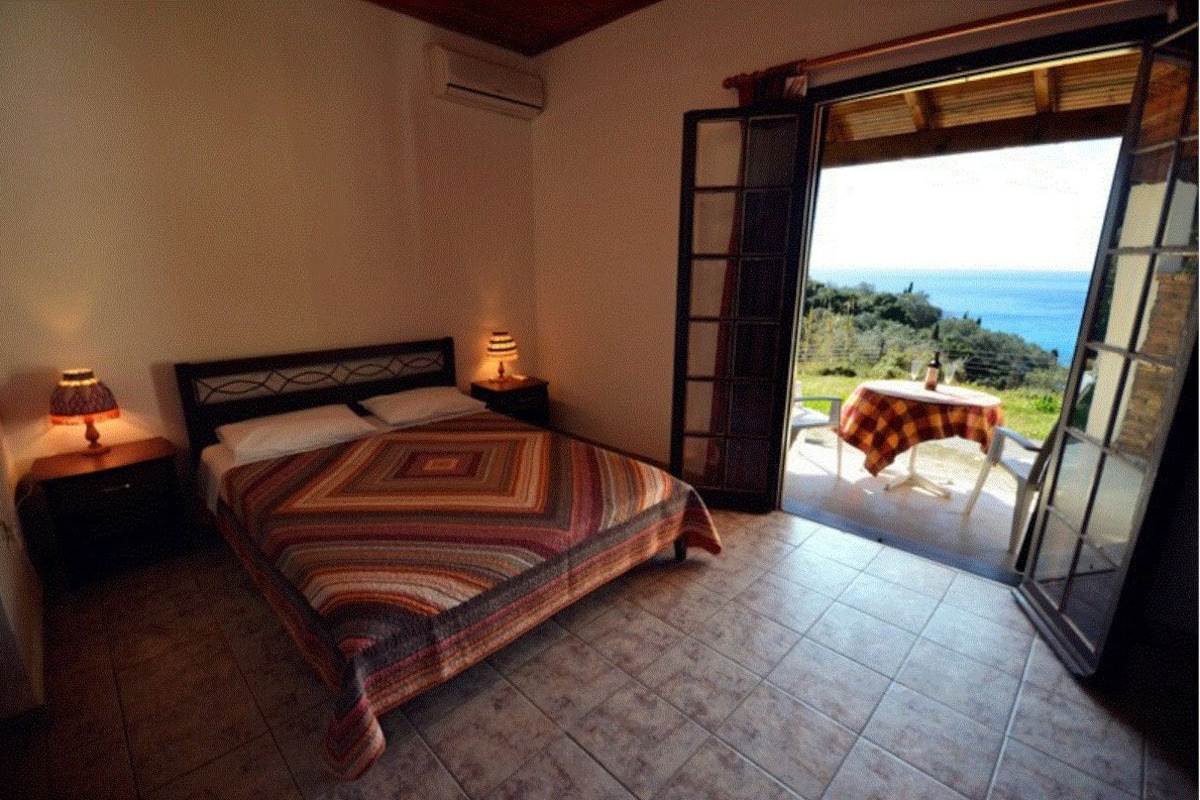 A bedroom with a bed, bedside lamps, and a view of the outdoors through a sliding door.