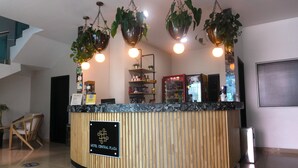 A reception desk with a sign reading "HOTEL CENTRAL PLAZA," surrounded by hanging plants and a Coca-Cola refrigerator. - Hotel Central Plaza Medellin (Itagüí)