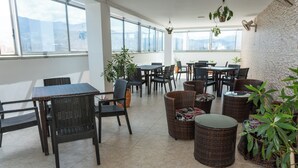 A spacious indoor area with multiple tables and chairs, large windows, and potted plants. - Hotel Central Plaza Medellin (Itagüí)