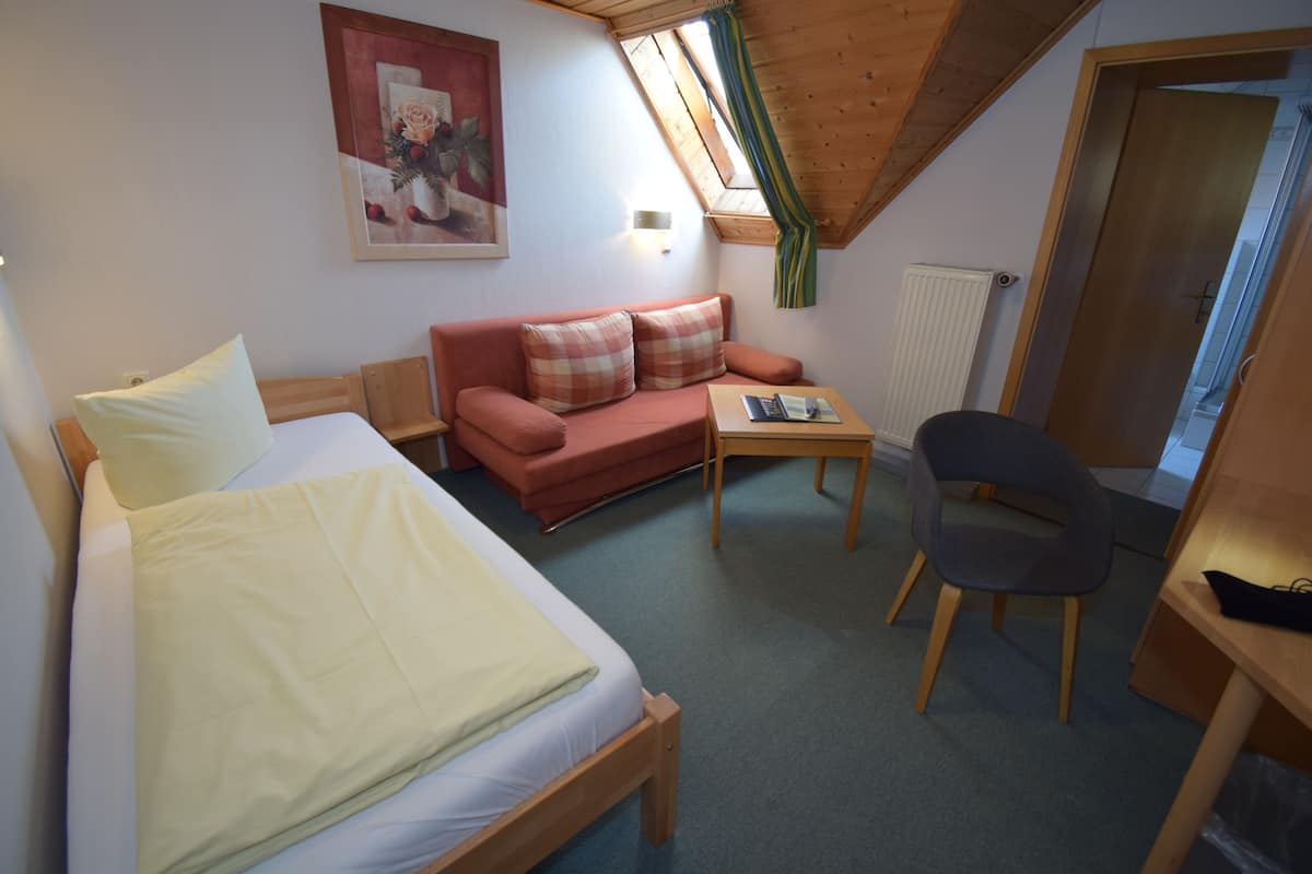 Een kamer met een bed, een bank, een bijzettafeltje, een stoel en een radiator.